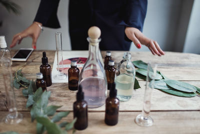 Midsection of mid adult female entrepreneur preparing perfume on table at workshop