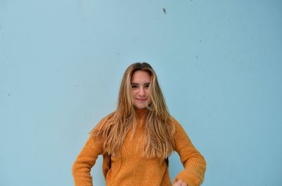 Portrait of young woman standing against blue sky