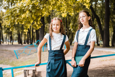 Two pupils in school uniform enjoy a walk in the park on a warm day