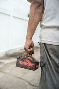 Cropped image of man holding metal while standing on footpath