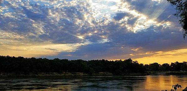 Scenic view of river against sky at sunset