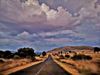 Empty road along landscape and against sky