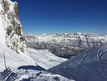 Scenic view of snowcapped mountains against clear blue sky