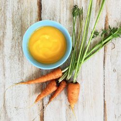 Top view of carrots and pure in bowl kept on wood