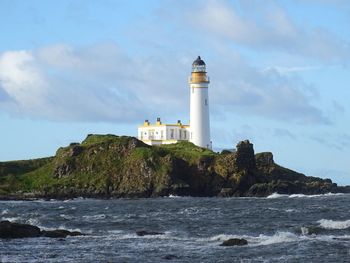 Lighthouse by sea against sky