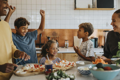 Happy boy cheering sister helping family in preparing food at home