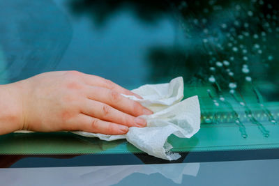 Cropped hand of woman cleaning car windshield