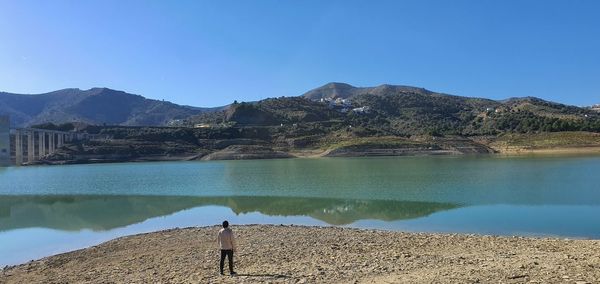 Scenic view of lake by mountains against clear blue sky