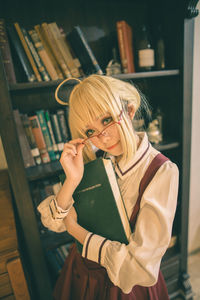 Portrait of woman with book standing at home