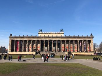 Group of people in front of built structure against blue sky