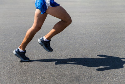 Legs male runner athlete run on gray asphalt