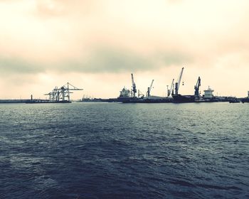Cranes at commercial dock against sky