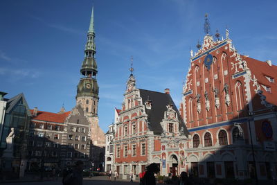 Low angle view of church by walkway against blue sky during sunny day