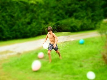 Rear view of shirtless man running on grass