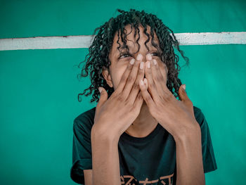 Portrait of person covering face against blue sky