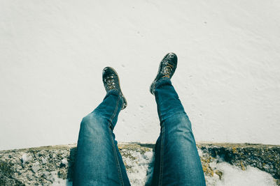 Low section of man sitting on retaining wall over snow during winter