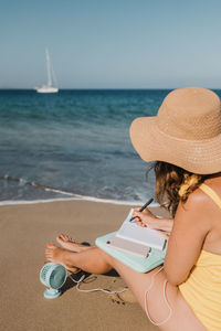 Side view of woman using laptop at beach