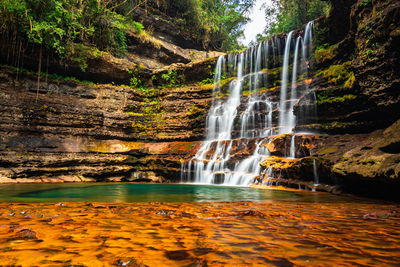 Waterfall streams falling from mountain with blurred water surface at morning from low angle