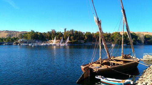 Boats moored in sea against clear blue sky