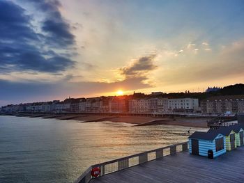 Buildings by sea against sky during sunset