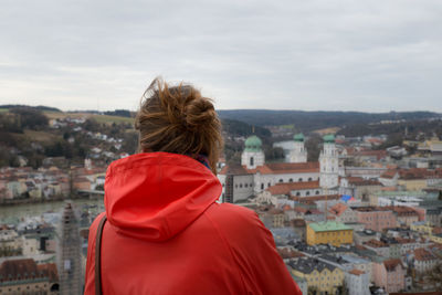 Rear view of woman looking at buildings in city against sky