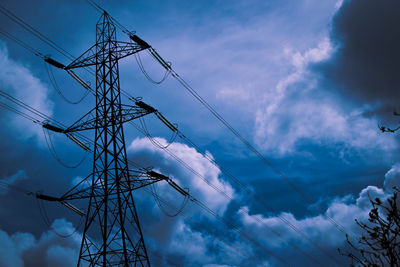 Low angle view of electricity pylon against cloudy sky