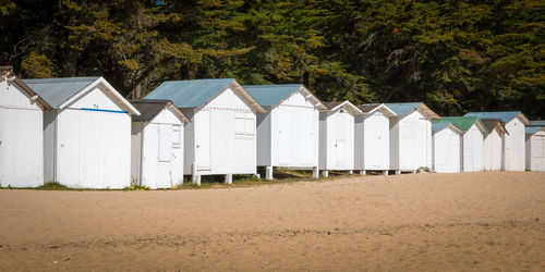 View of beach huts against trees and buildings