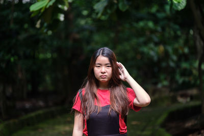 Portrait of young woman standing against trees