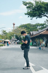 Young man traveller prepare his camera equipment ,standing on the walking street