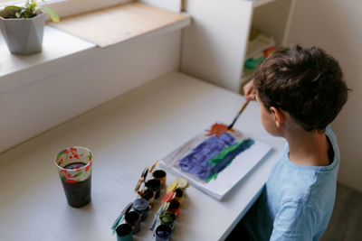 High angle view of boy painting at home