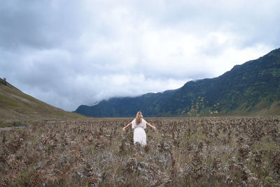 Rear view of woman standing on field against sky