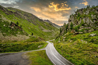 Road amidst green landscape against sky