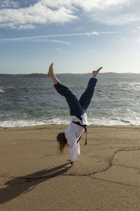 Woman cartwheeling in kimono on the beach