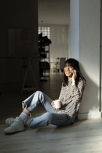 Female professional talking on smart phone while leaning on column