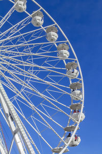 Low angle view of ferris wheel against blue sky