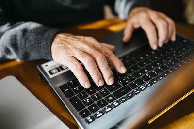 Hands of senior man using laptop, close-up
