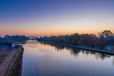 Scenic view of river against sky at sunset