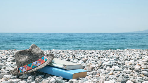 Books and male straw hat on the pebble beach. concept of reading and relaxing in summer vacation. 
