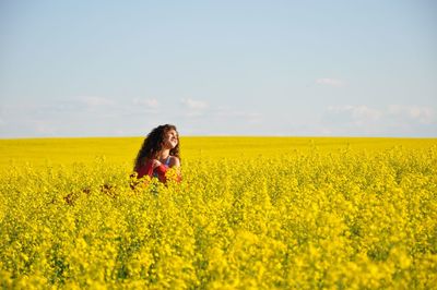 Teenage girl in oilseed rape field against sky