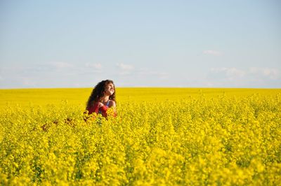 Teenage girl in oilseed rape field against sky