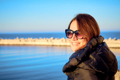 Young woman wearing sunglasses against sea