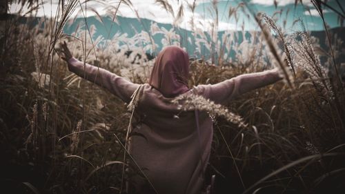 Young woman standing on field against trees