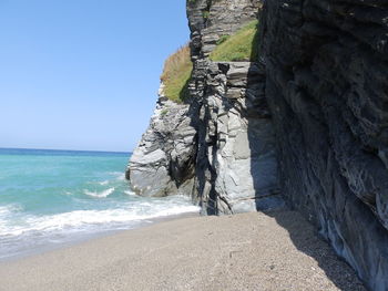 Rock formations on beach against clear sky