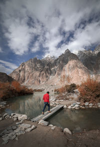 Rear view of man walking on mountain against sky