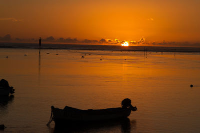 Silhouette boat in sea against orange sky