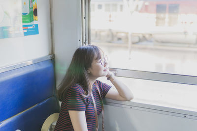 Side view of woman looking away through train window