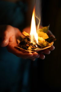 Close-up of hand holding lit candle