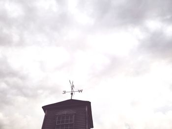 Low angle view of weather vane against building