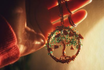 Close-up of hand holding illuminated pendant and chain