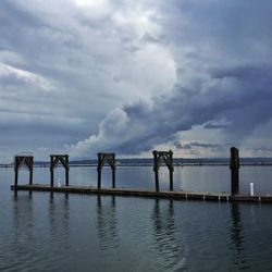 Pier on sea against cloudy sky